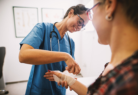 A physician bandaging a patient's hand