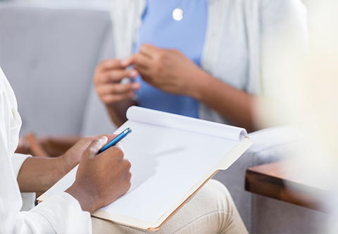 A physician taking notes while speaking to a patient